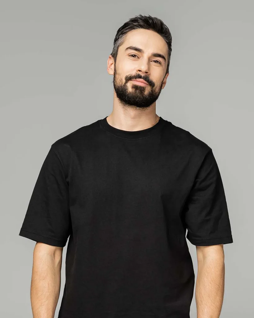 Nauczyciel online w czarnym t-shircie na neutralnym tle.